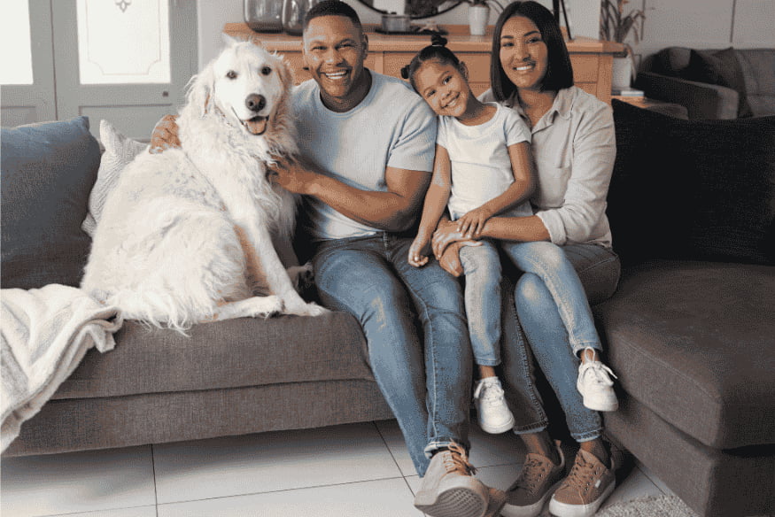 Família feliz sentada no sofá ao lado de um cachorro de grande porte, simbolizando o vínculo afetivo e a segurança proporcionada pelo RG Pet.