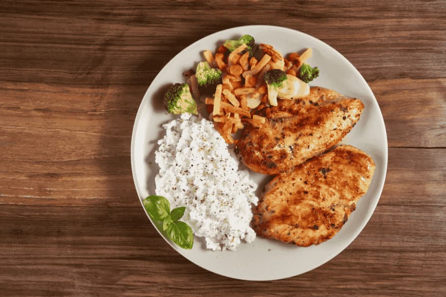 Prato com frango, arroz e legumes, exemplo de refeição natural que pode ser adaptada para a dieta caseira de cães.