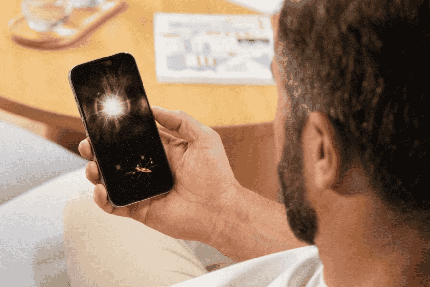 Pessoa segurando celular com imagem de espaço na tela, representando o uso de aplicativo para identificar estrelas e planetas de forma prática.