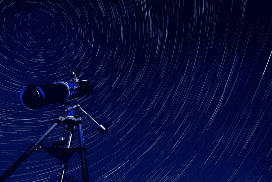 Telescópio apontado para o céu com trilhas de estrelas circulares ao fundo, ilustrando técnica de longa exposição para fotografar star trails.