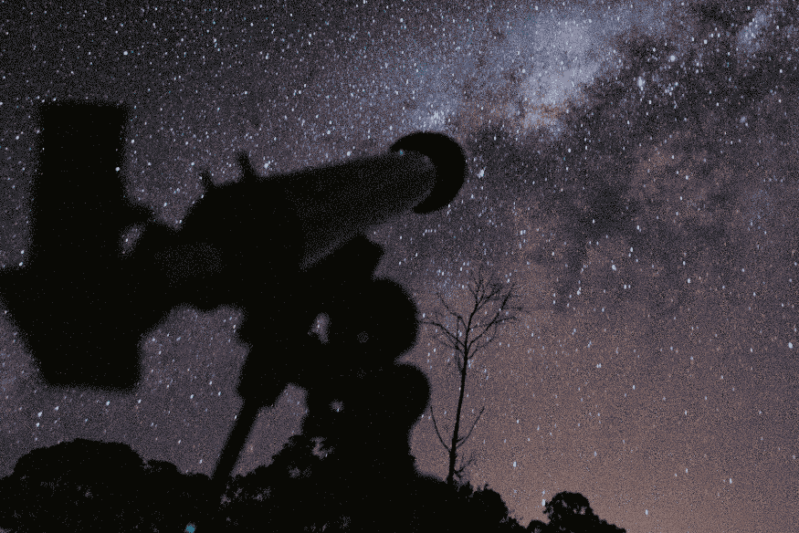 Telescópio apontado para céu estrelado com a Via Láctea ao fundo, ilustrando a busca por foco preciso durante observação astronômica noturna.