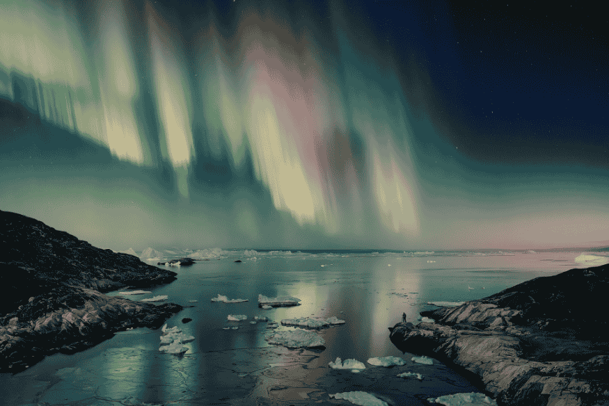 Aurora boreal refletida sobre água gelada com blocos de gelo e costa rochosa, em cena noturna de longa exposição.