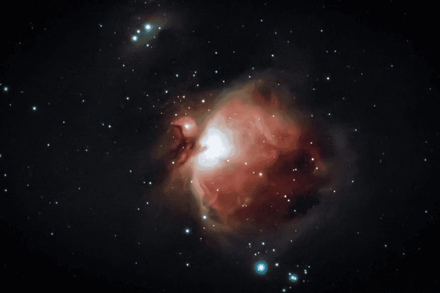 Nebulosa brilhante em tons avermelhados e rosados cercada por estrelas, exemplo de alvo clássico para astrofotografia de nebulosas.