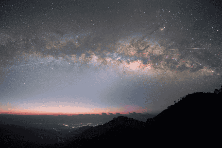Luz zodiacal visível como um cone luminoso subindo do horizonte antes do amanhecer, com a Via Láctea atravessando o céu estrelado.