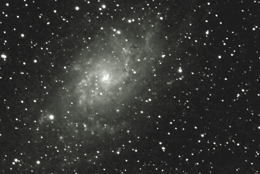 Campo espacial com galáxia difusa e inúmeras estrelas, imagem associada à busca por informações sobre atmosferas de exoplanetas na missão Ariel.