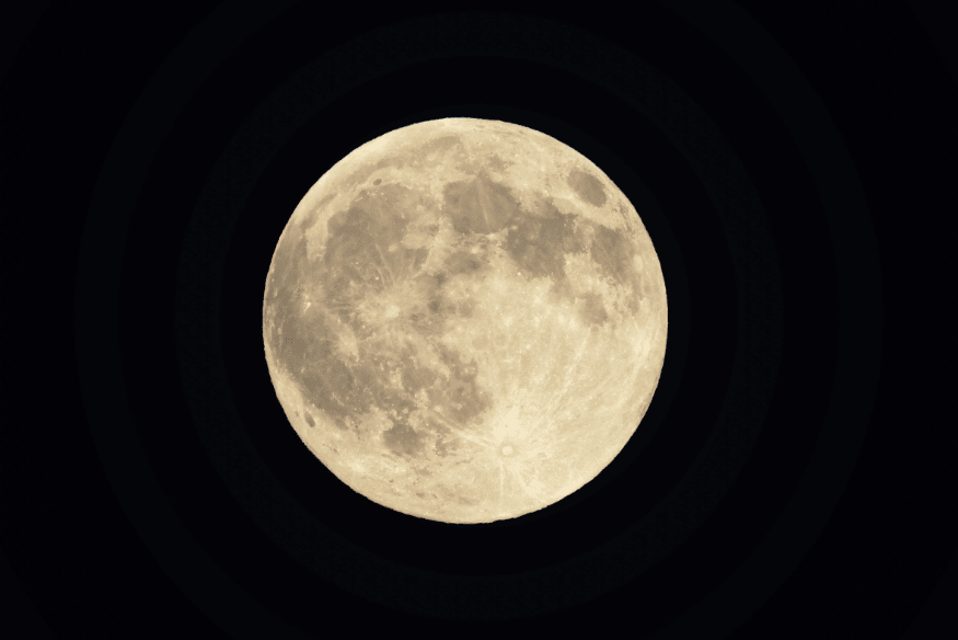 Lua cheia vista em close, com crateras e mares lunares visíveis, destacada contra um fundo preto.