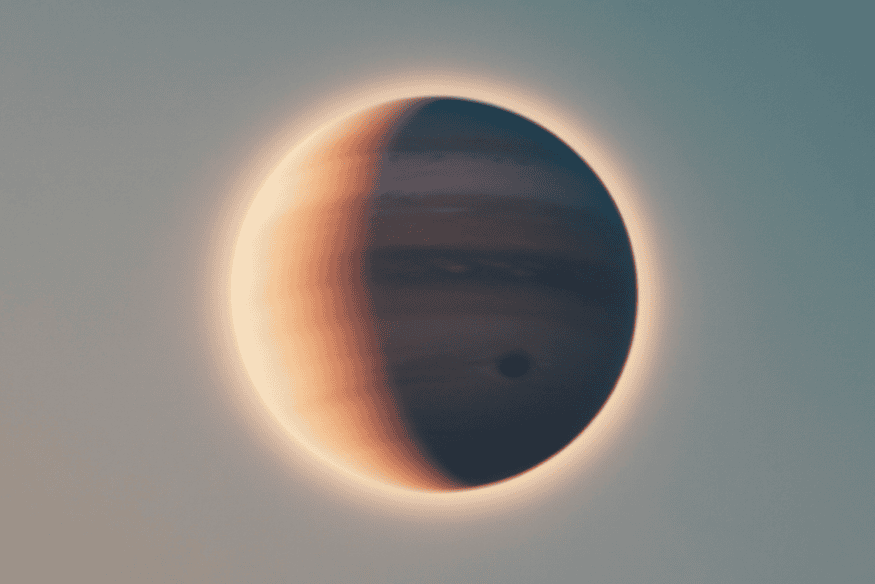 Júpiter parcialmente iluminado, com halo ao redor do planeta e detalhe escuro na atmosfera, destacando suas tempestades e camadas de nuvens.