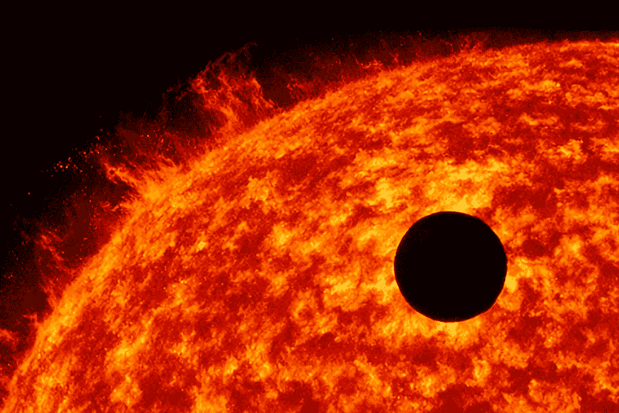 Trânsito planetário em close sobre a superfície brilhante de uma estrela, com o planeta aparecendo como um disco escuro à frente do astro.