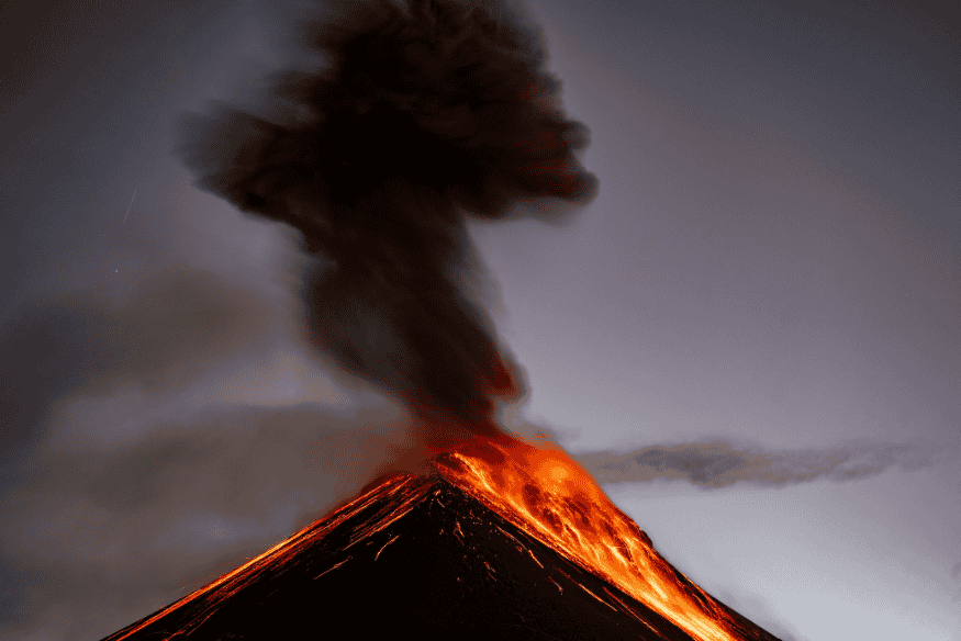 Vulcão em erupção na superfície de Io, com lava brilhante e pluma escura subindo acima do relevo.