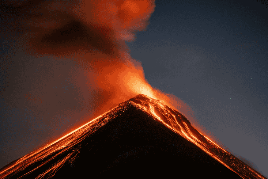 Erupção vulcânica em Io com lava incandescente descendo pelas encostas e grande pluma iluminada acima da cratera.
